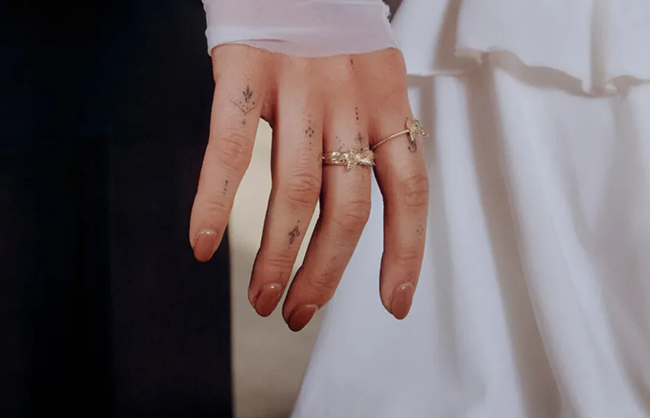 Hand with jewelry and fine-line tattoos representing the Chronic Ink color direction.
