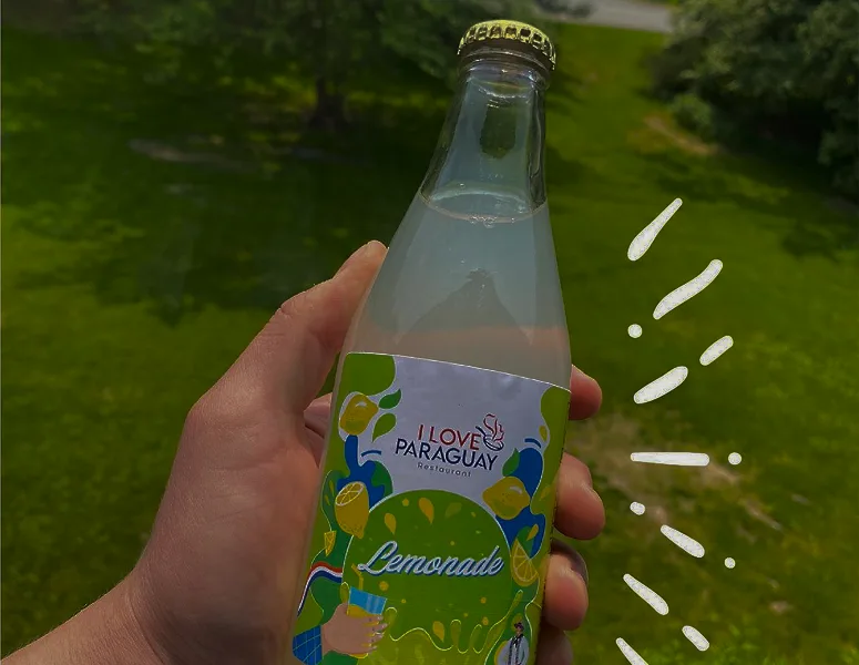 I love Paraguay branded lemonade bottle held outdoors.